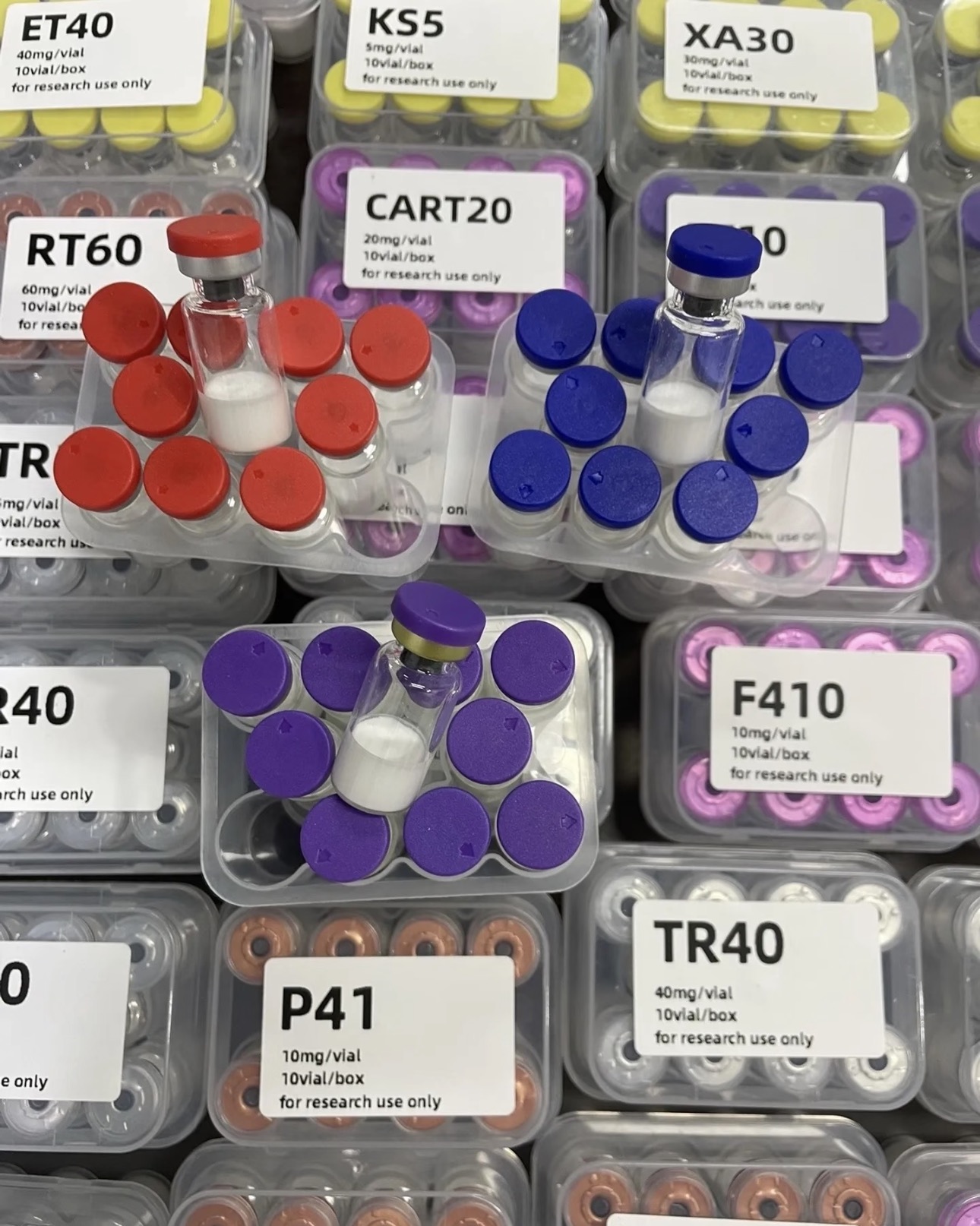 Assorted research peptide vials with color-coded caps in labeled trays.